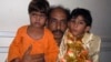کراچی ایک پولیس اسٹیشن میں سات سالہ دولہا وسیم اور چار سالہ دلہن نیشا، اور ان کا والد اسماعیل۔ پولیس نے انہیں شادی کے موقع پر چھاپہ مار کر گرفتار کیا۔ فائل فوٹو
